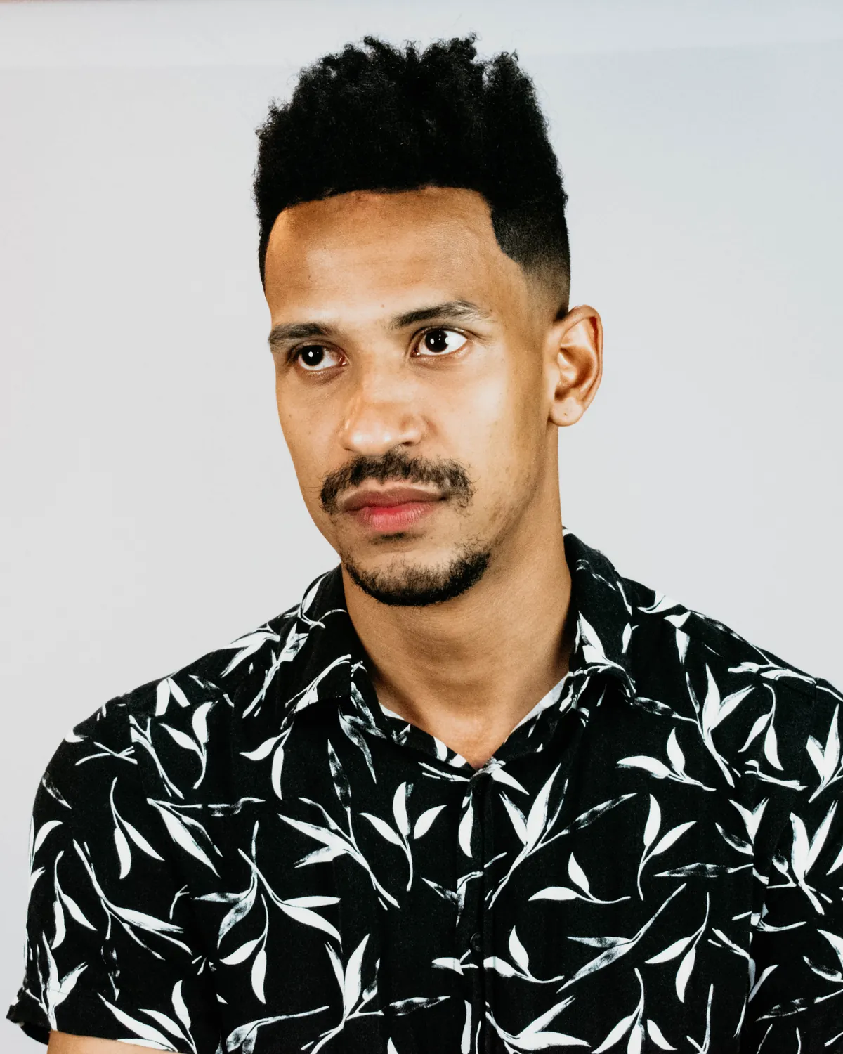 Prince Andre, retrato de camisa preta estampada, olhando para o lado