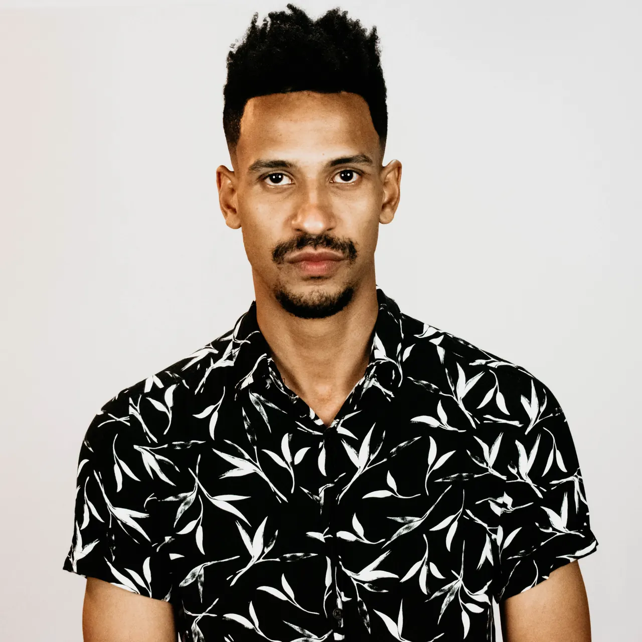 Prince Andre de frente, camisa preta estampada com folhas brancas